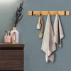 A bathroom scene with a wooden towel rack holding towels and brushes, next to a vanity with toiletries. Produktbild-Vorschau