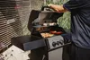 A person is grilling food on a gas grill outdoors. Produktbild-Vorschau