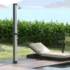 An outdoor shower and lounge chair by a body of water. Náhľad obrázku produktu