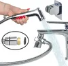 A hand holding a bidet shower head with water spraying, connected to a faucet via a hose. A mounting bracket is also visible. Náhľad obrázku produktu