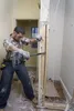 A man is using a demolition tool to break down a wall. Podgląd zdjęcia produktu