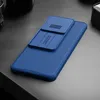 A blue phone case with a sliding camera cover is placed on a dark gray surface. Produktbild-Vorschau
