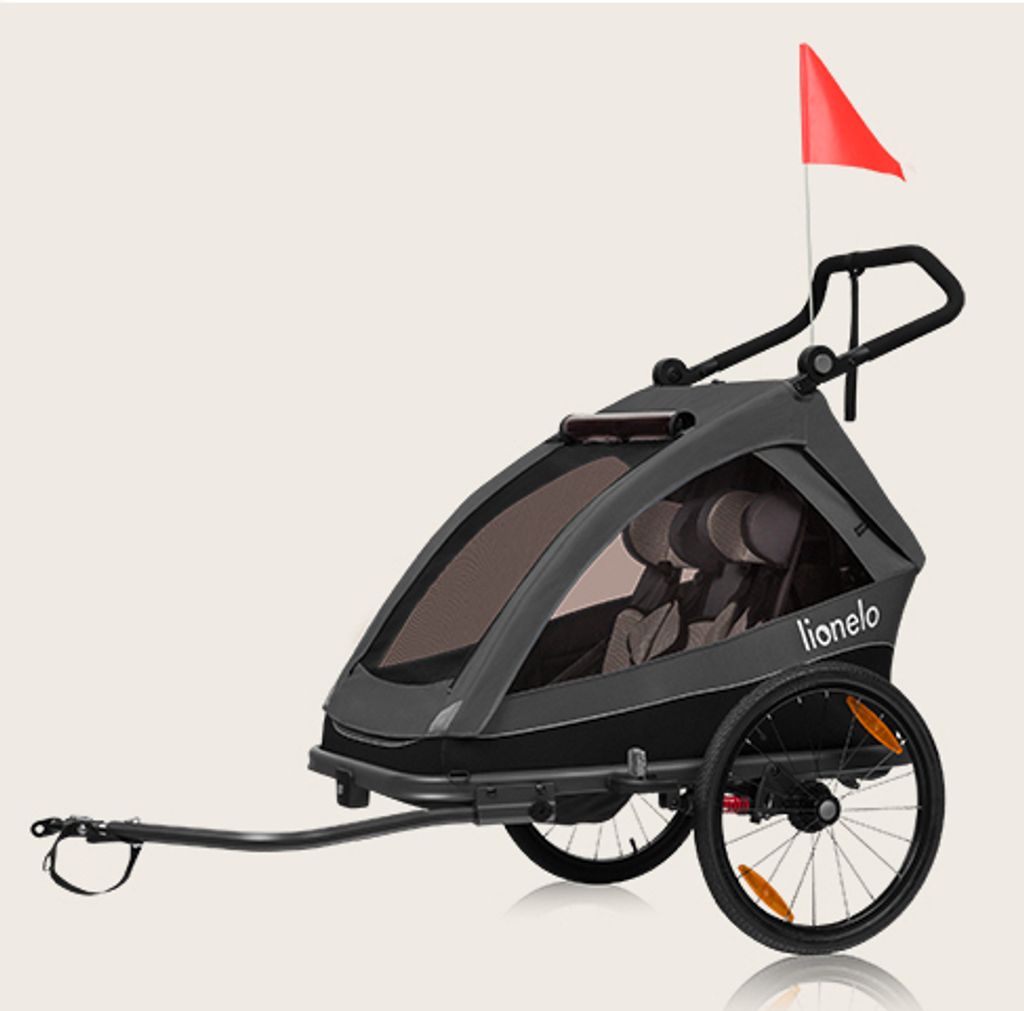A gray and black child trailer for bicycles or as a stroller, with a red flag on top.