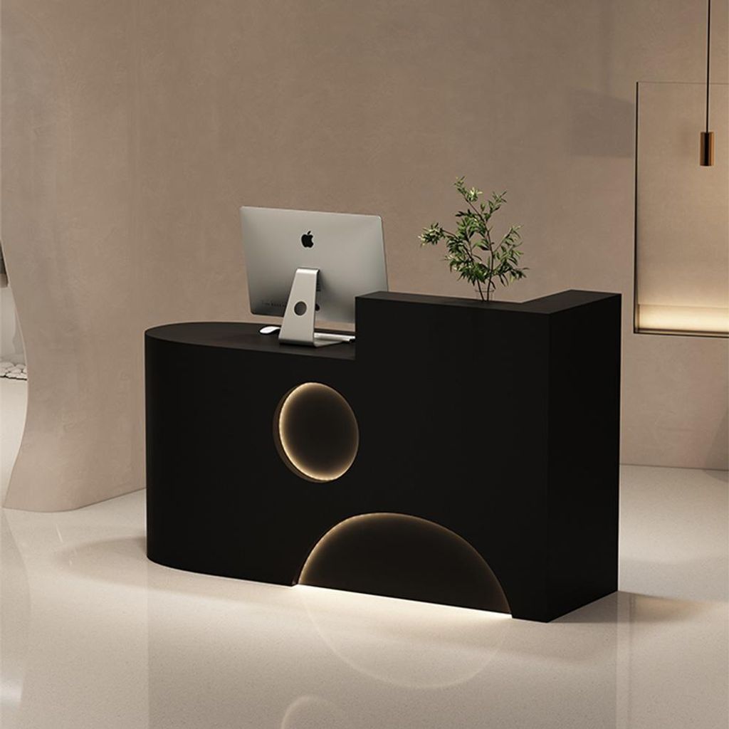 A modern black reception desk with integrated lighting and a computer.