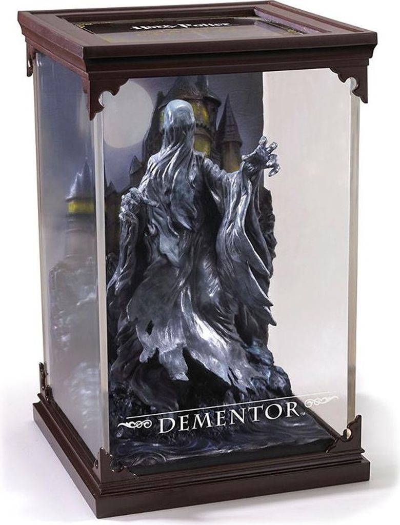 A Dementor figurine in a display case with a castle and moon background.