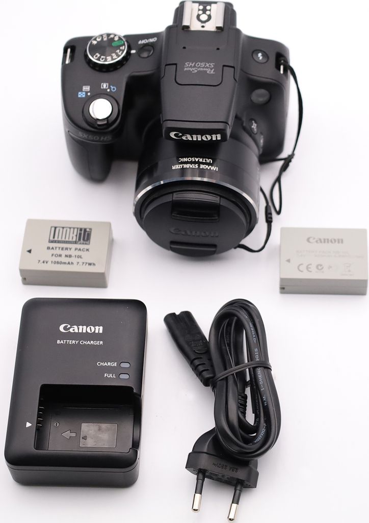A Canon PowerShot SX50 HS digital camera and its accessories are laid out on a white background.