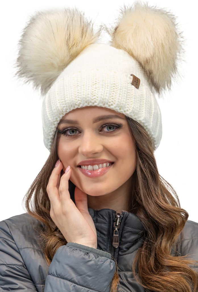 A woman wearing a winter hat with two pom-poms.