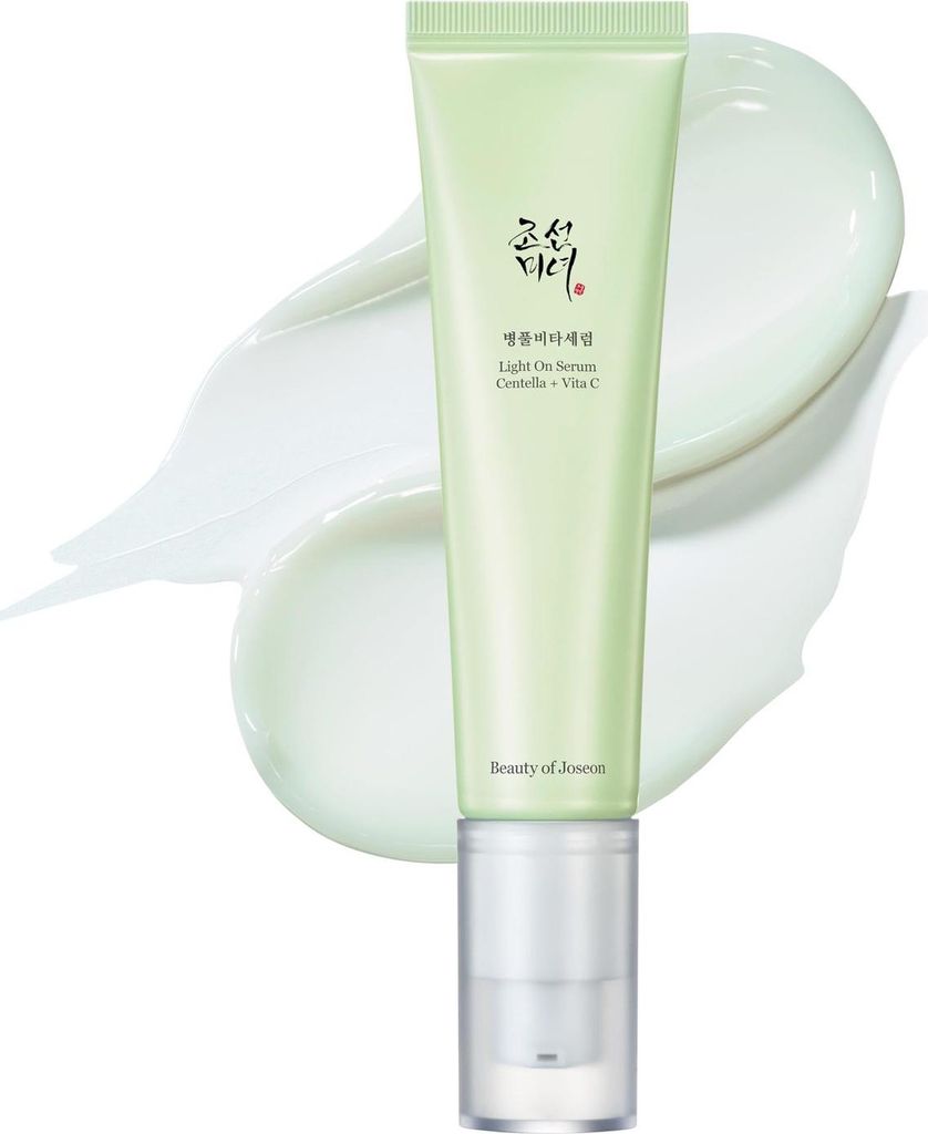 A light green tube of serum with a clear pump dispenser, placed on a white background with swirls of white cream.