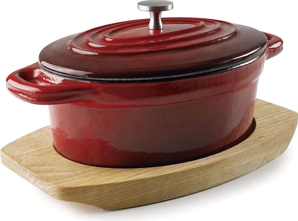 A red oval casserole dish with a lid sits on a wooden trivet against a white background.