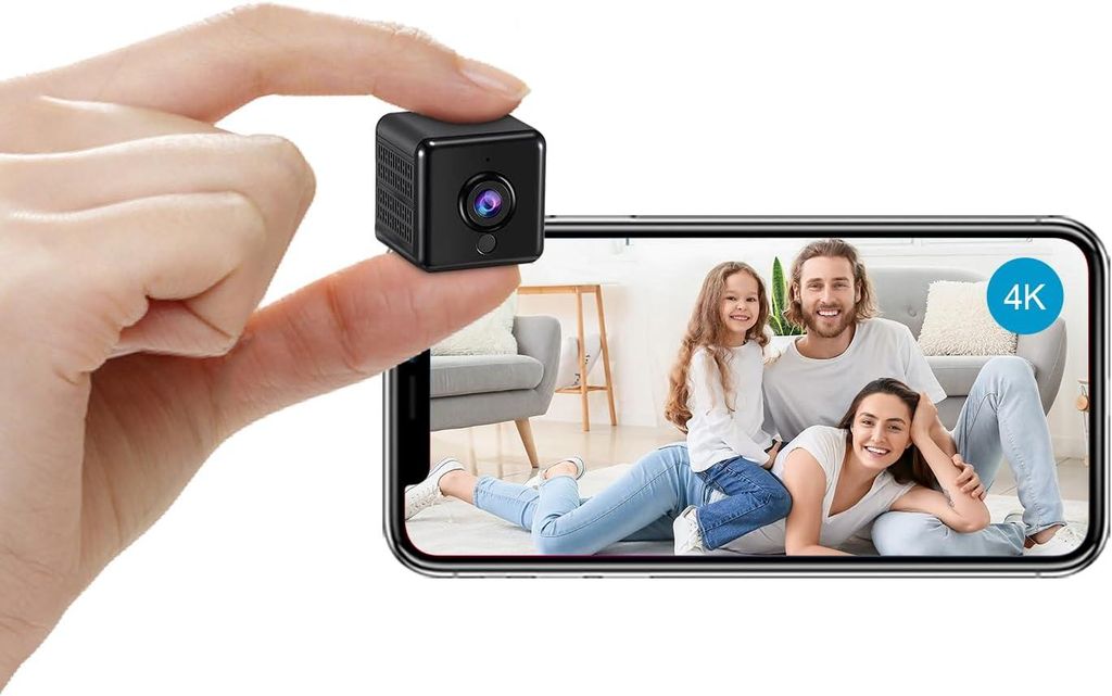 A hand holds a mini camera over a smartphone displaying a family video.