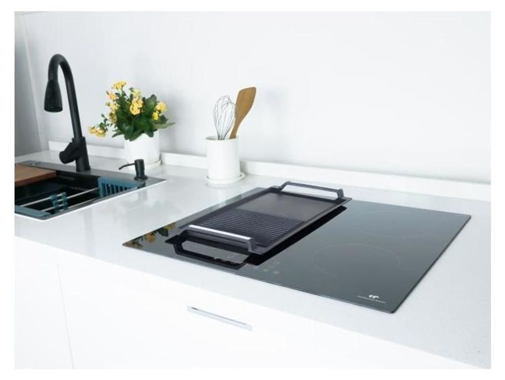 A modern kitchen countertop with a sink and a black induction cooktop.