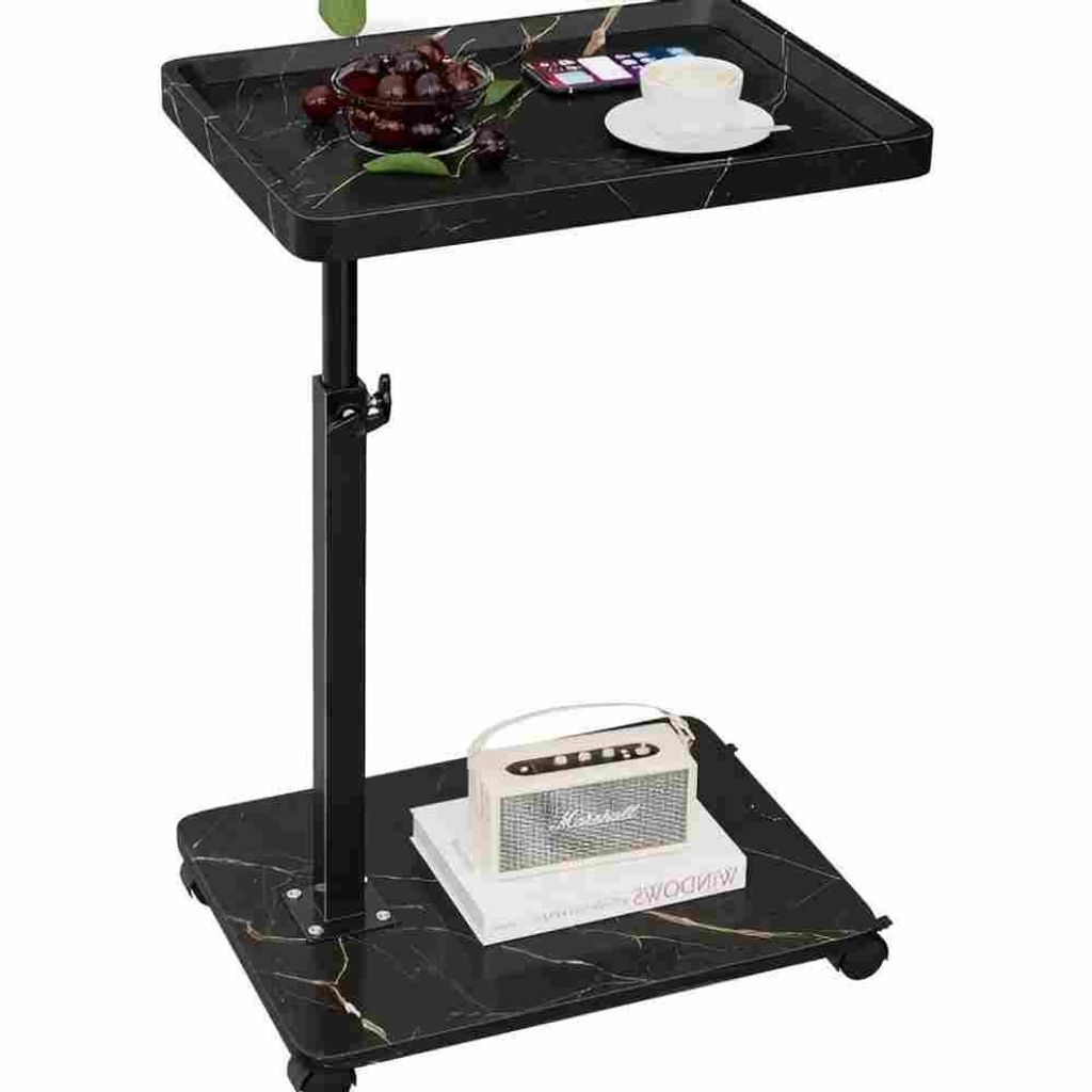 A black marble-patterned C-shaped side table with adjustable height, shown with a bowl of cherries, a smartphone, and a cup of coffee on the top surface, and a small speaker on a book on the lower shelf.