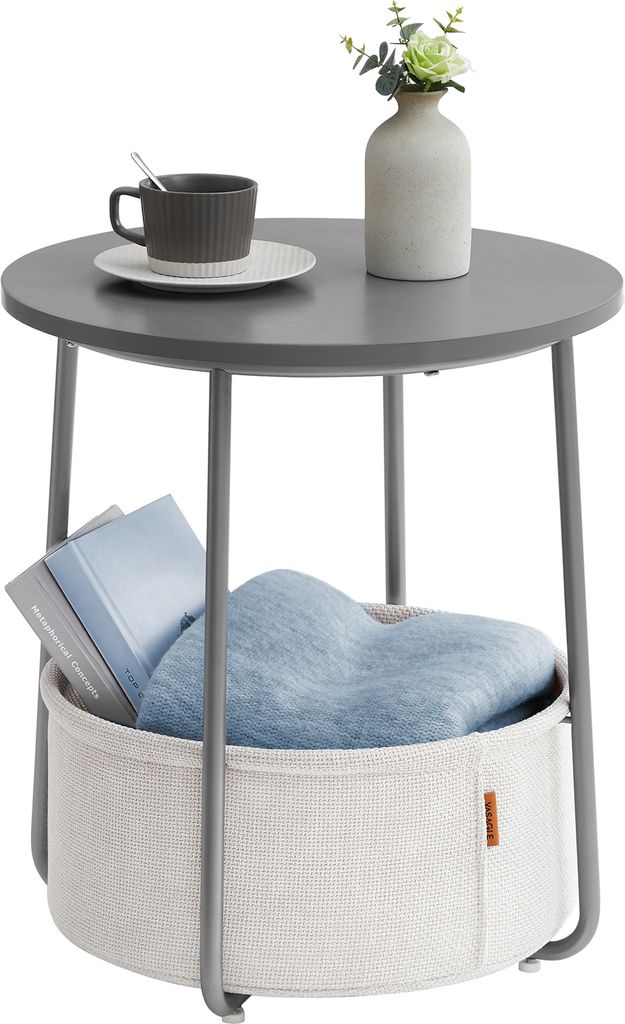 A round gray side table with a storage basket underneath, holding books and a blue blanket.