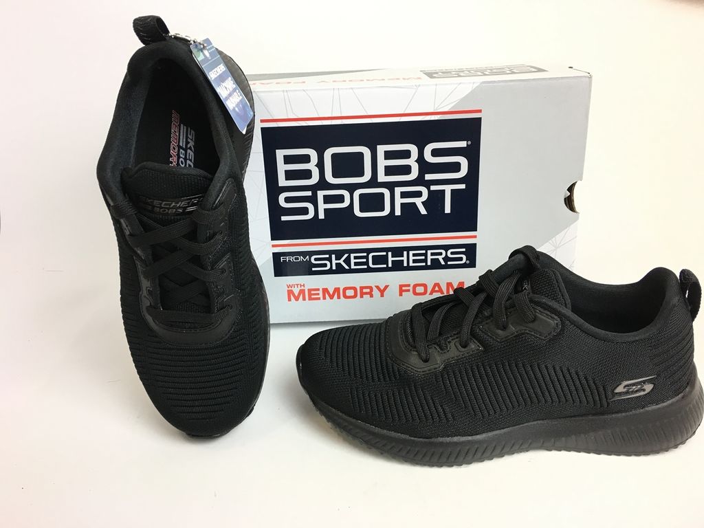 A pair of black Skechers Bobs Squad sneakers are displayed next to their original packaging.