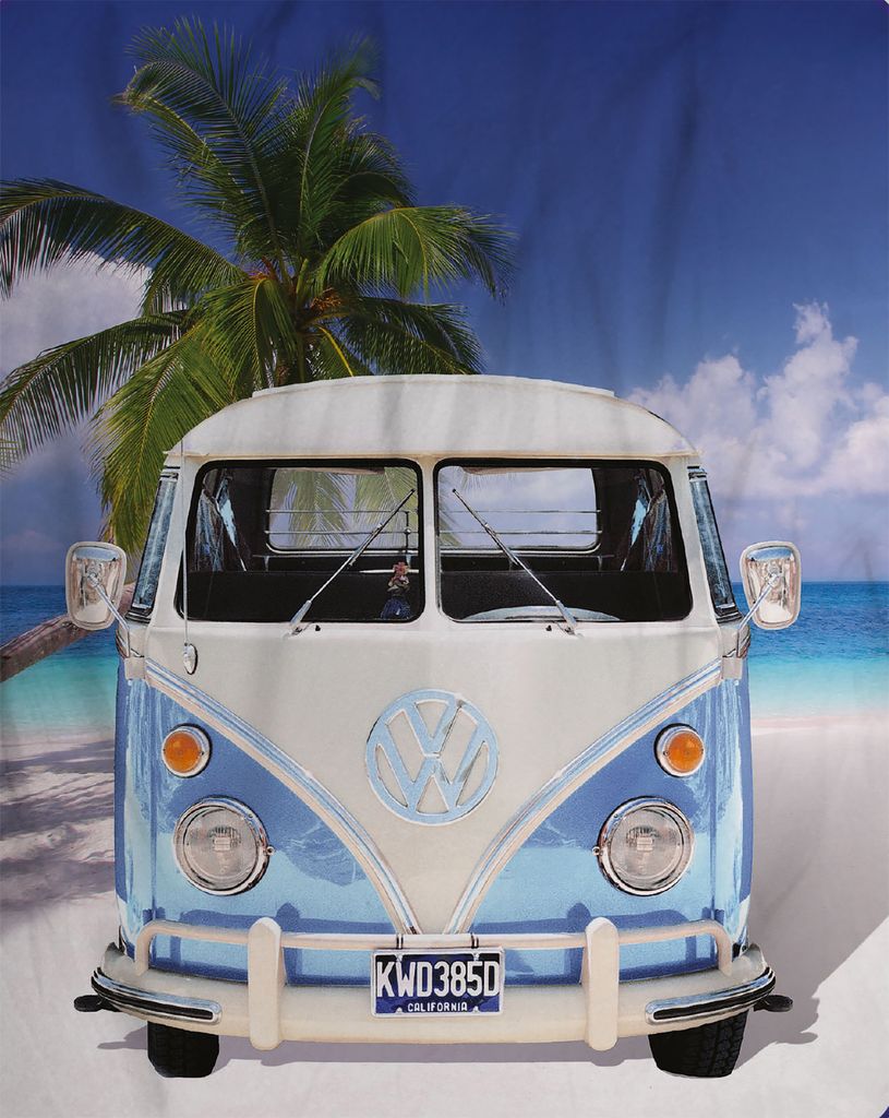 A vintage Volkswagen van on a beach with a palm tree.
