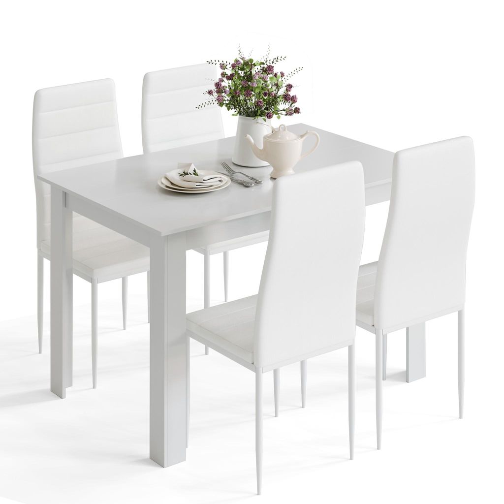 A white dining table with four white chairs, set with a plate, cutlery, a teapot, and a vase of flowers.