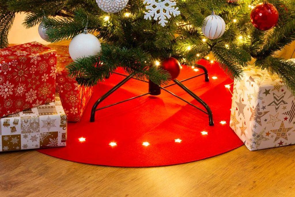 A Christmas tree skirt with lights and presents underneath.