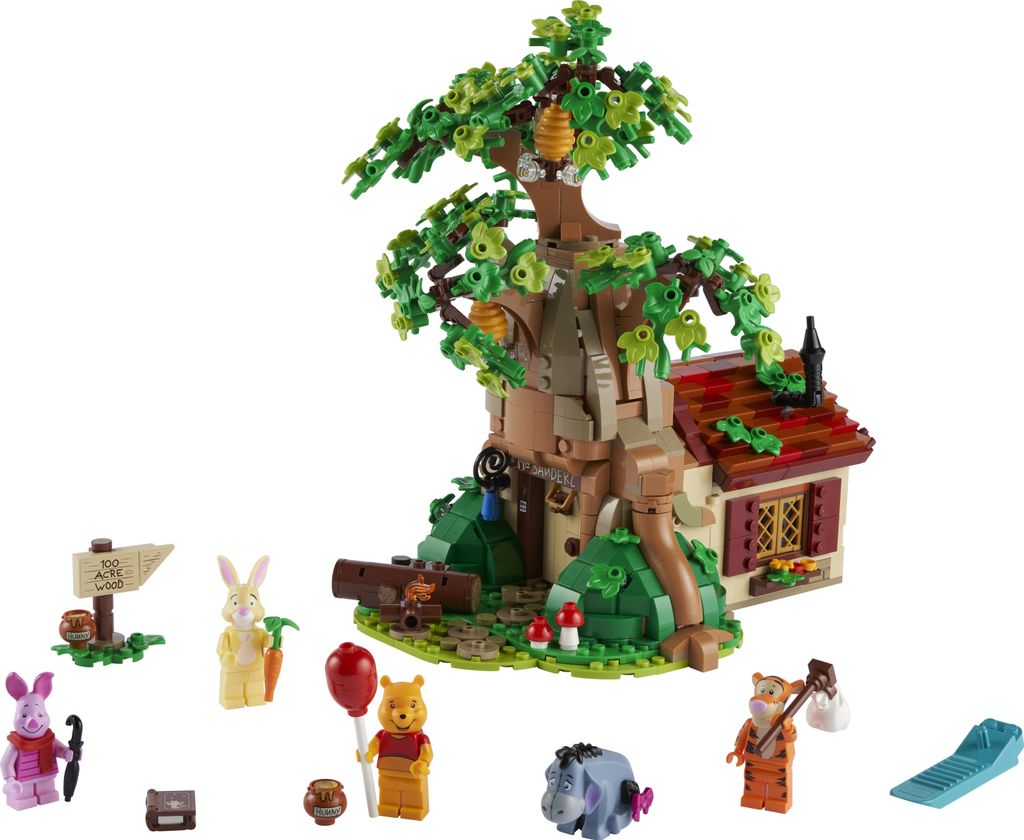 A LEGO set depicting Winnie the Pooh's house in the Hundred Acre Wood, with various characters and accessories arranged around it.