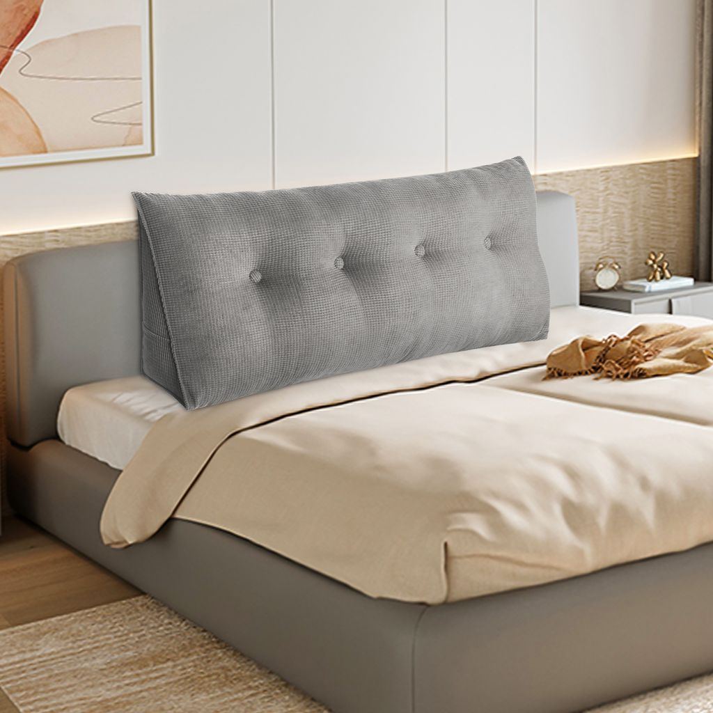 A grey wedge pillow is placed on a bed.