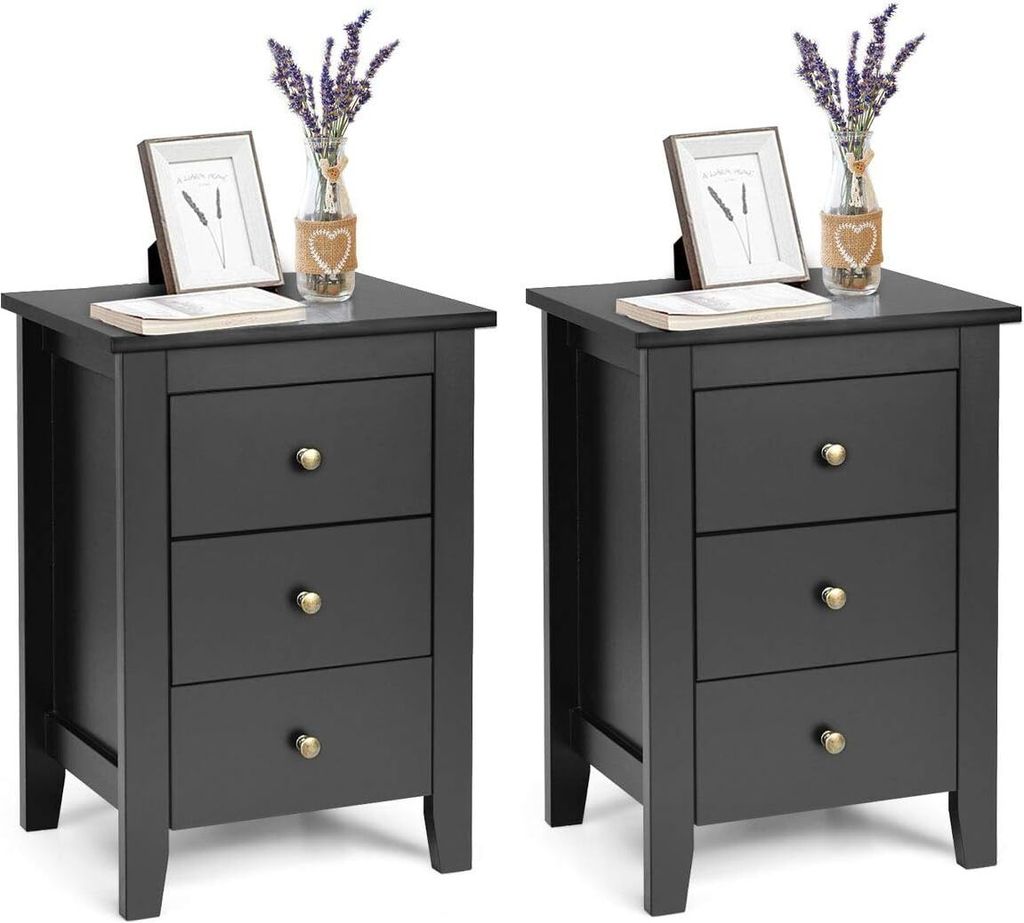 Two identical black nightstands are shown against a white background. Each nightstand has three drawers with gold knobs. On top of each nightstand, there is a framed picture, a small vase with dried flowers, and a book.