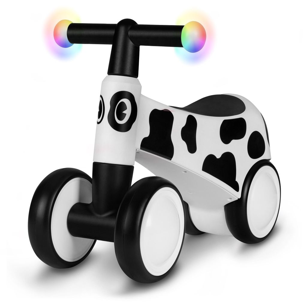 A white and black cow-patterned balance bike with colorful lights on the handlebars, shown against a white background.