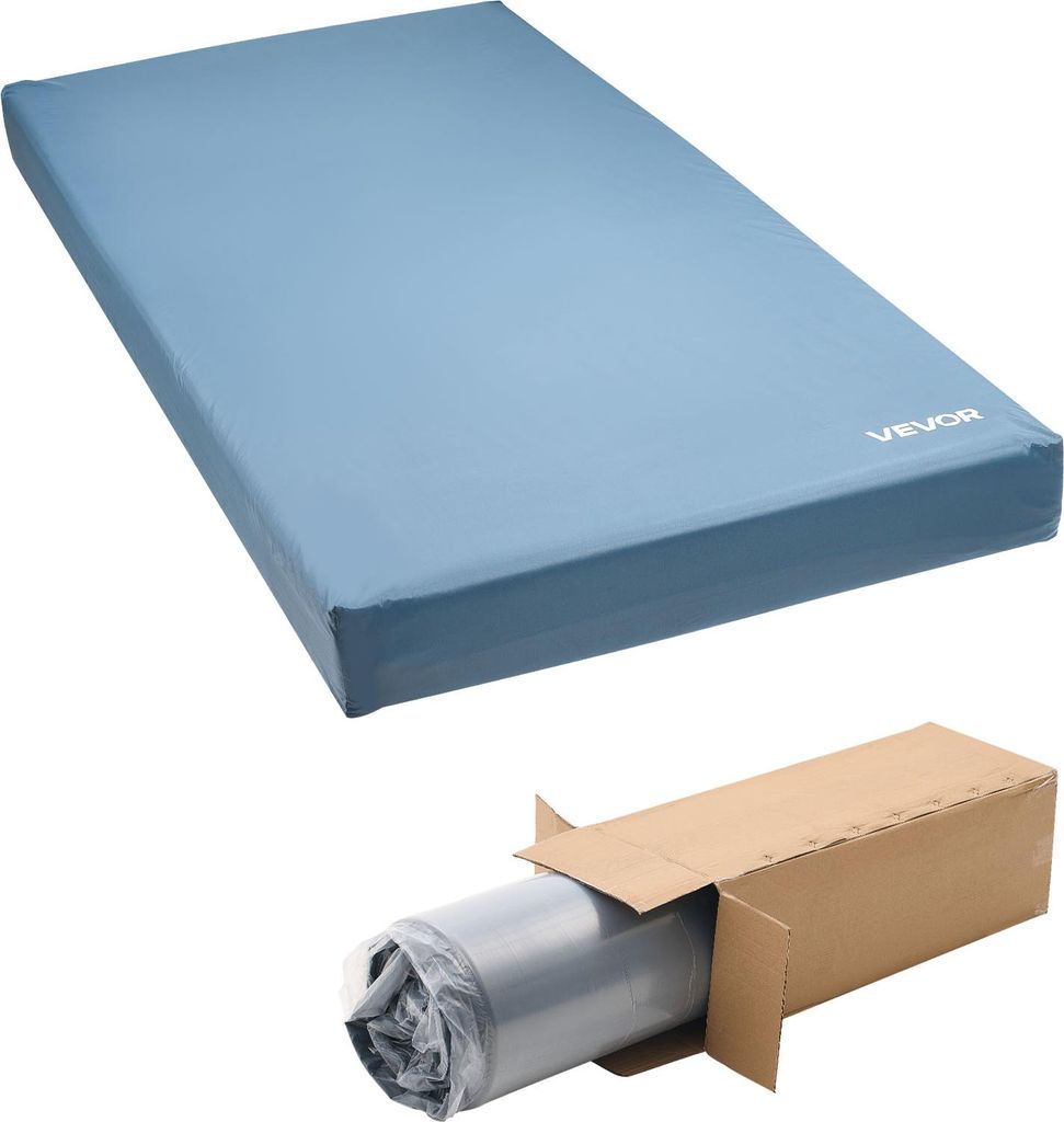 A blue mattress is shown from a diagonal angle, with a cardboard box containing a rolled-up gray item in the bottom right corner.