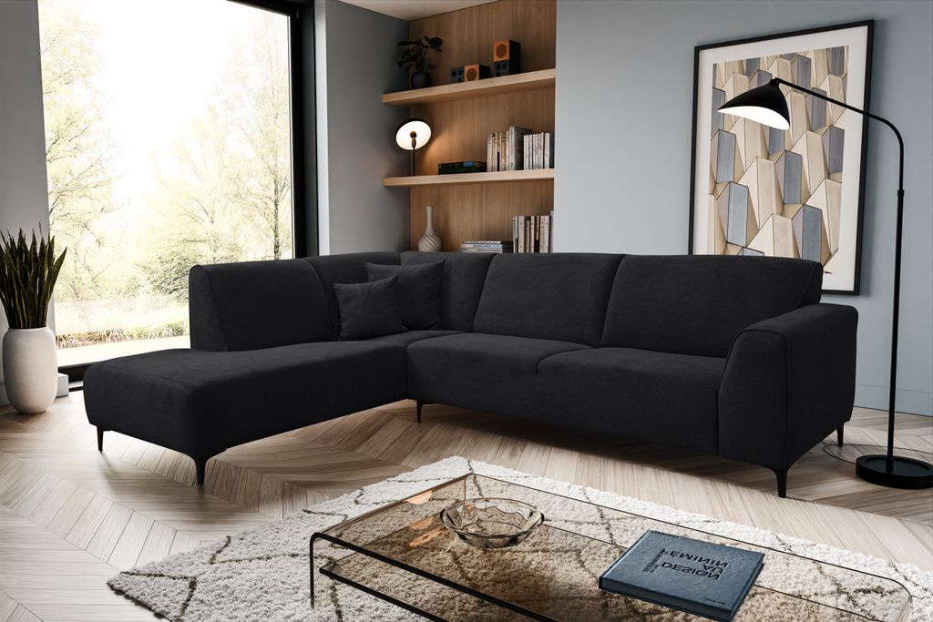 A modern living room with a black sectional sofa, coffee table, and shelves.