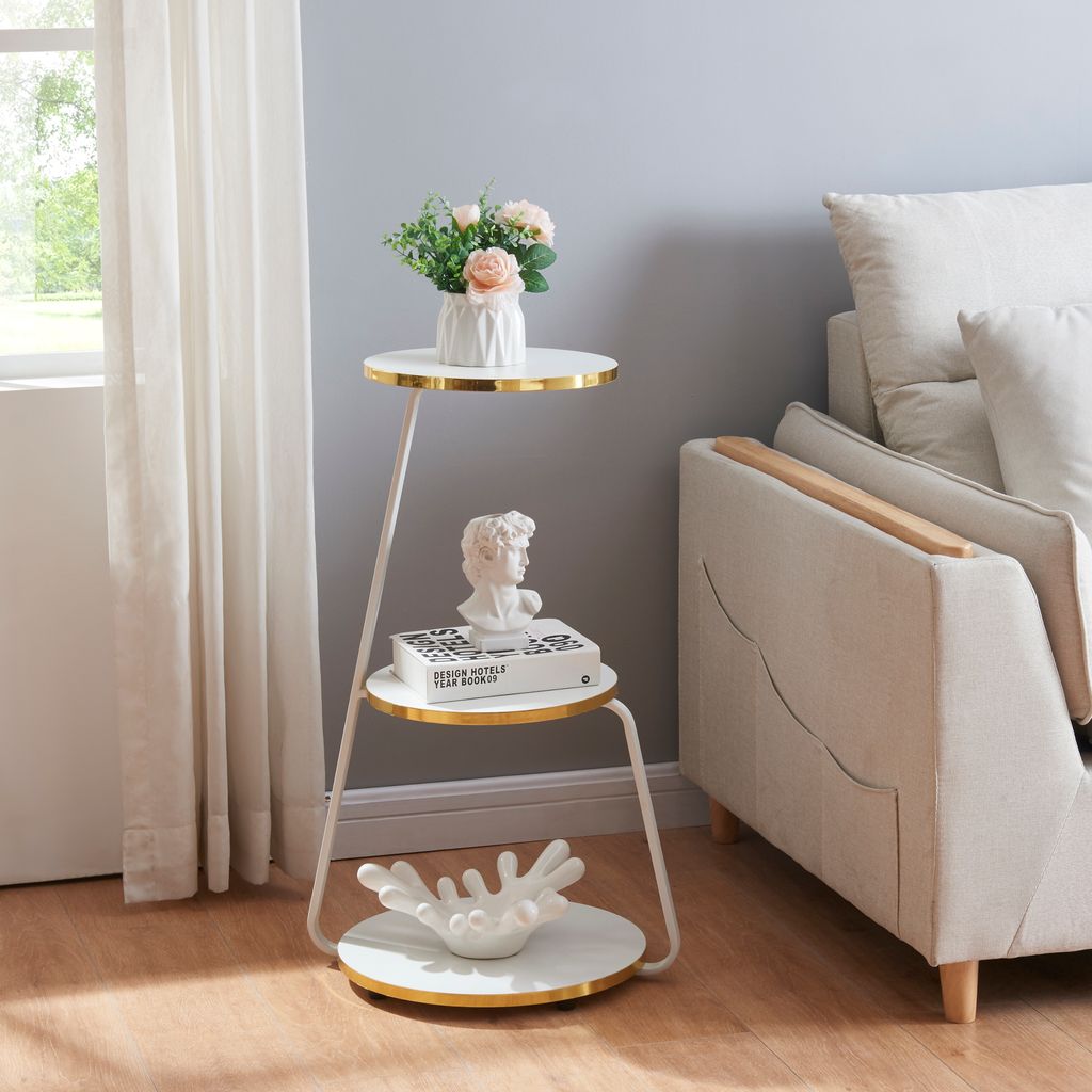 A three-tiered side table with decorative items is placed next to a sofa.