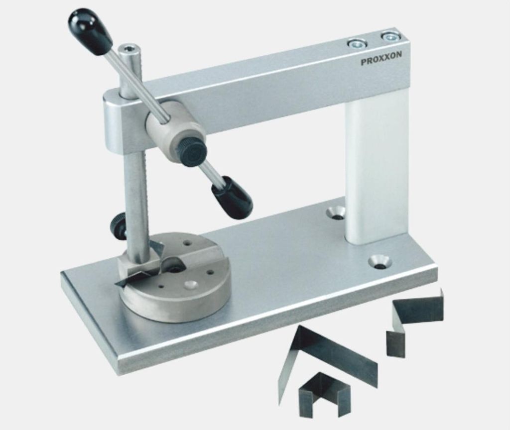 A metal workbench tool with black handles and several small metal pieces on a light gray background.