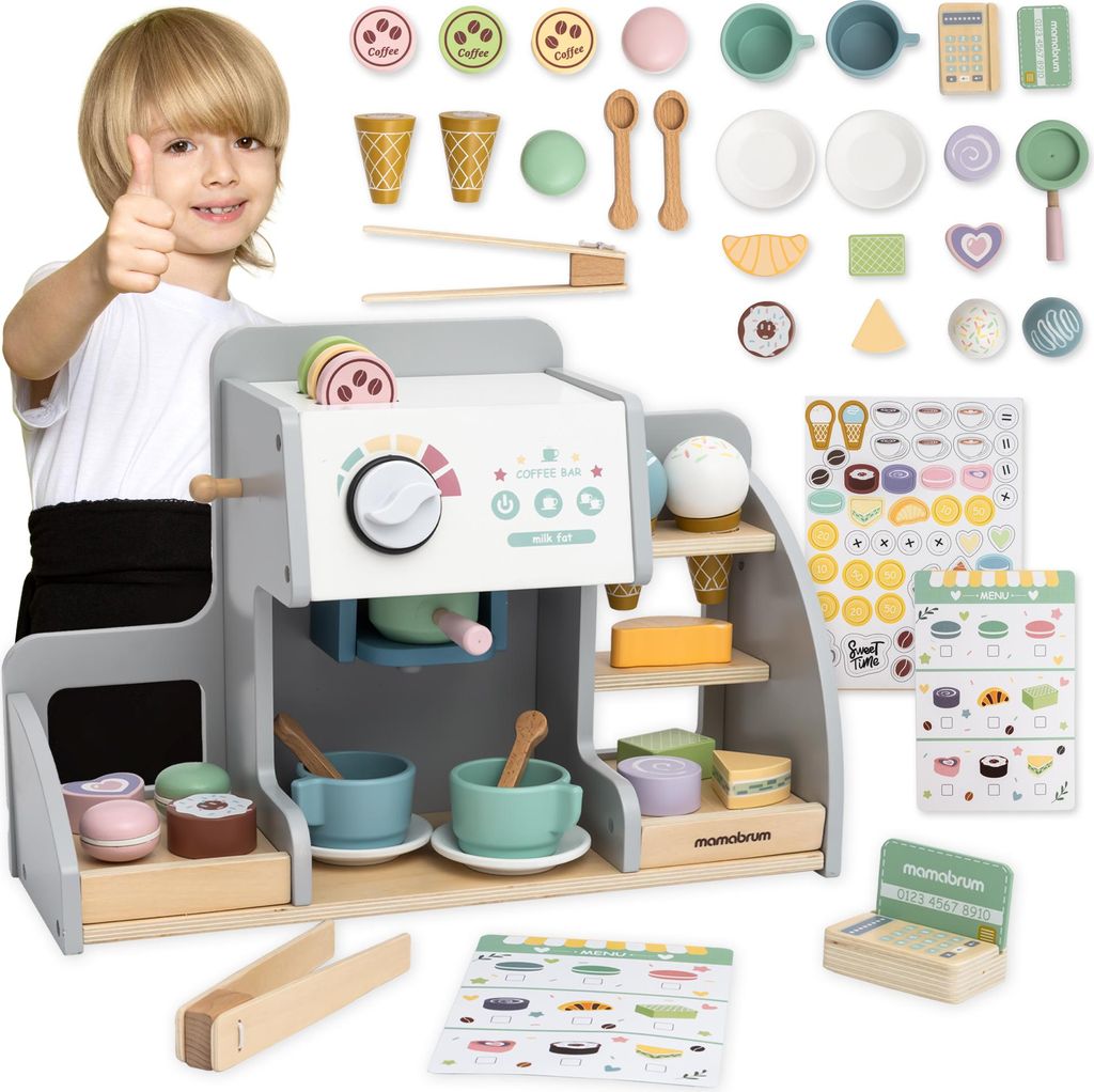 A child is giving a thumbs up next to a wooden coffee and ice cream bar playset.