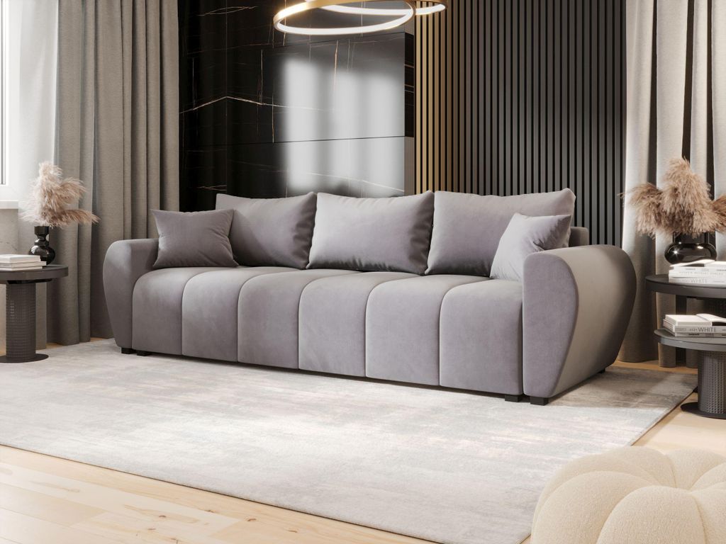 A modern living room with a large gray sofa, decorative pillows, and a rug.