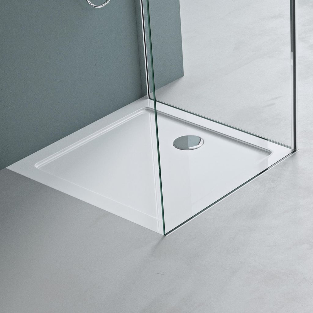 A close-up view of a white rectangular shower tray with a drain, enclosed by glass shower walls.