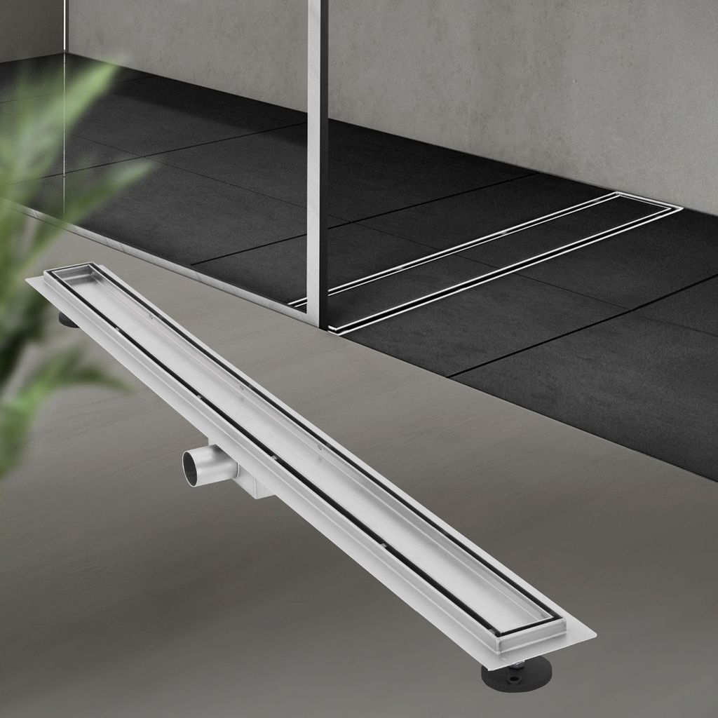 A linear shower drain is shown in the foreground, with a tiled shower area in the background.