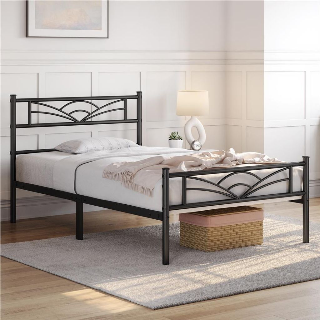 A black metal bed frame with a decorative headboard and footboard is shown in a bedroom setting.