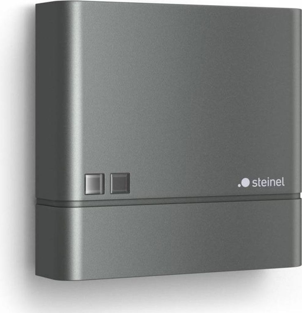 A dark gray electronic device mounted on a white wall.