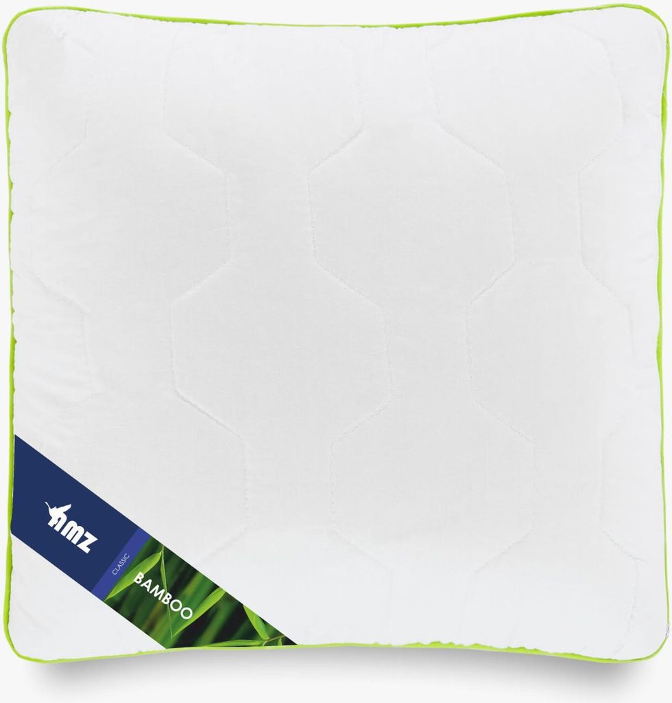A white quilted pillow with a green trim and a blue label with text and an image of bamboo leaves.