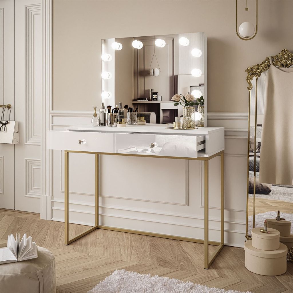 A modern vanity table with a lighted mirror, makeup, and decorative items in a well-lit room.