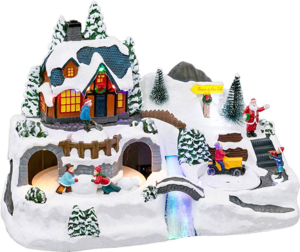 A festive Christmas village scene with a house, Santa, children playing in the snow, a tractor, and a waterfall.