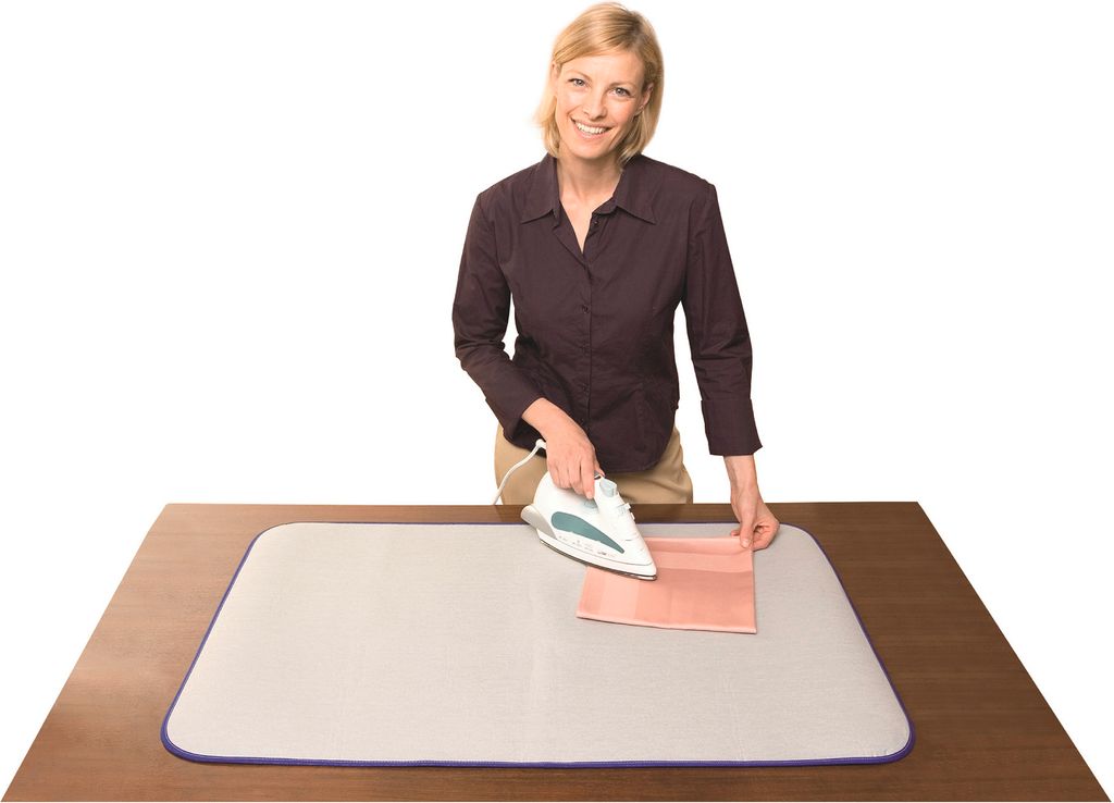 A woman is ironing a piece of fabric on a table with an ironing mat.