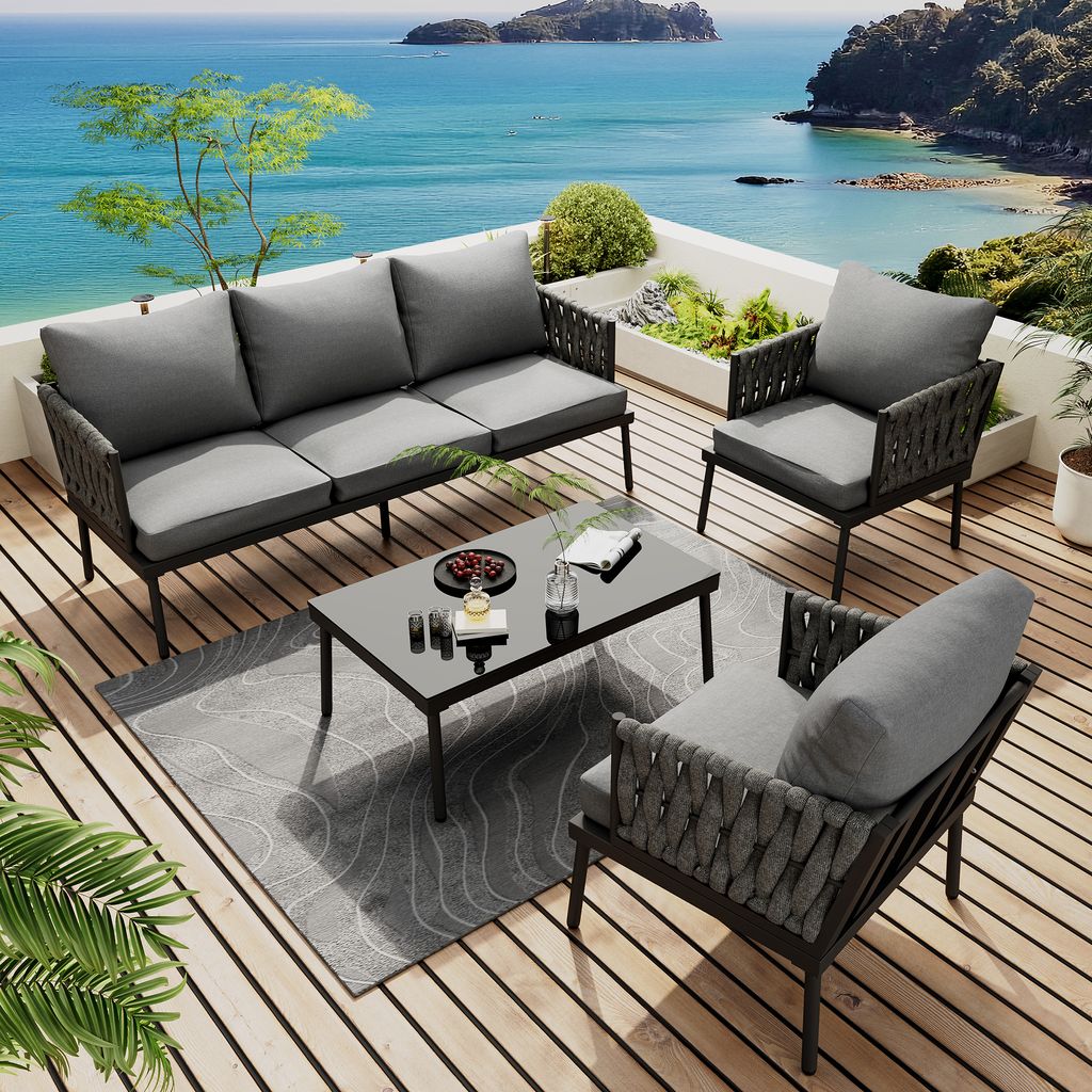 A patio furniture set on a wooden deck overlooking the ocean.