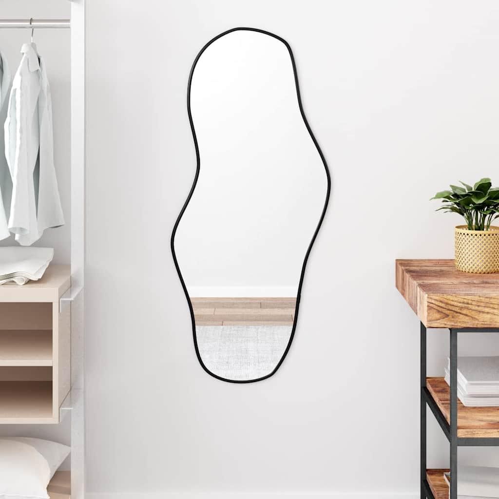 A mirror is hanging on a white wall next to a closet and a wooden table.