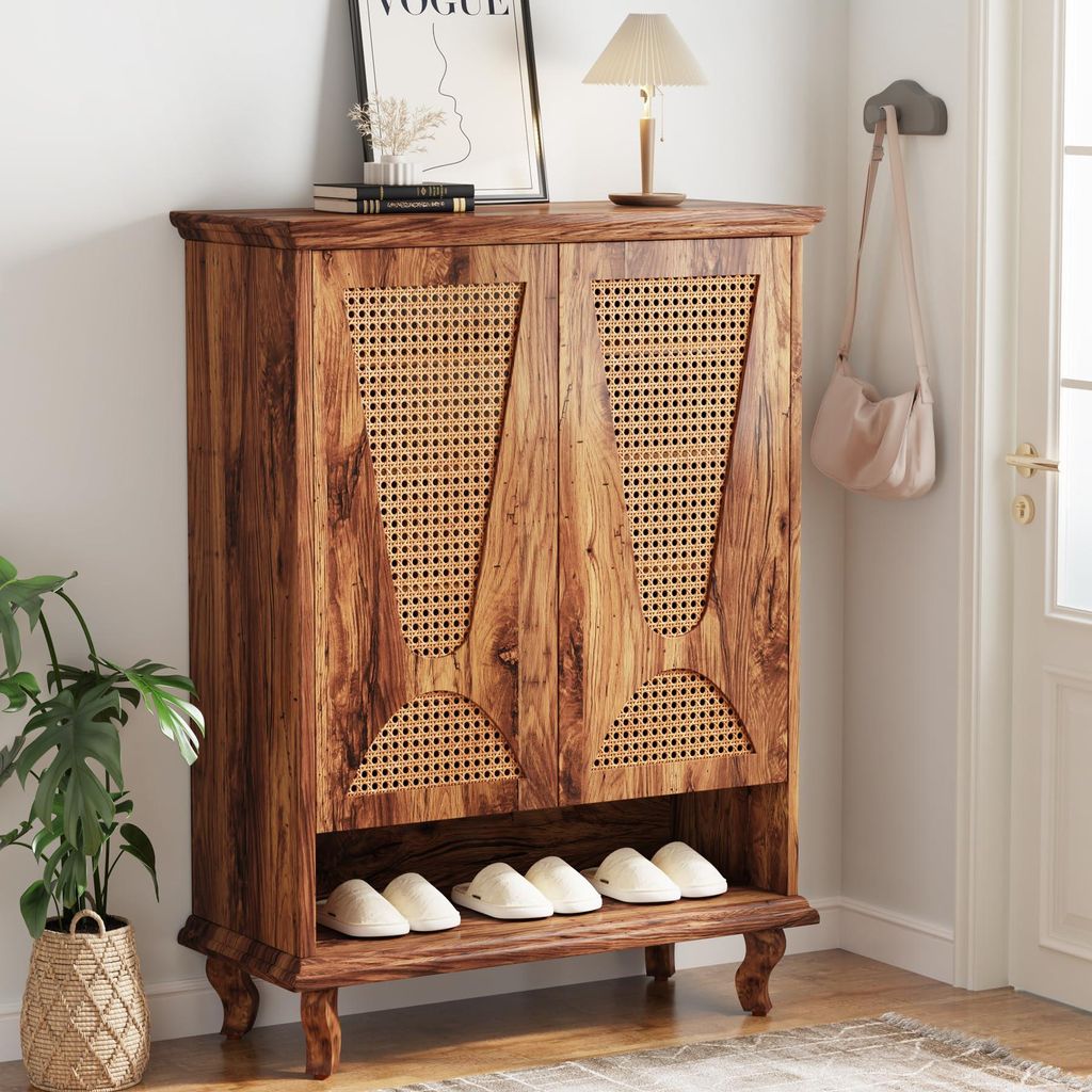A wooden shoe cabinet with rattan doors is shown in a hallway, with shoes on the bottom shelf and a plant and lamp on top.