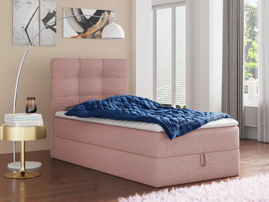 A pink upholstered bed with a blue blanket is shown in a bedroom setting.