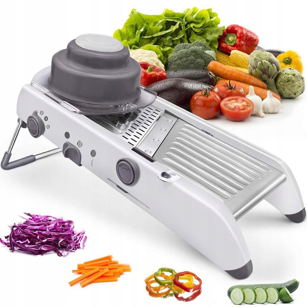 A white mandoline slicer is displayed prominently in the foreground, with a variety of fresh vegetables arranged in the background and around the slicer. Sliced vegetables are also shown in the foreground.