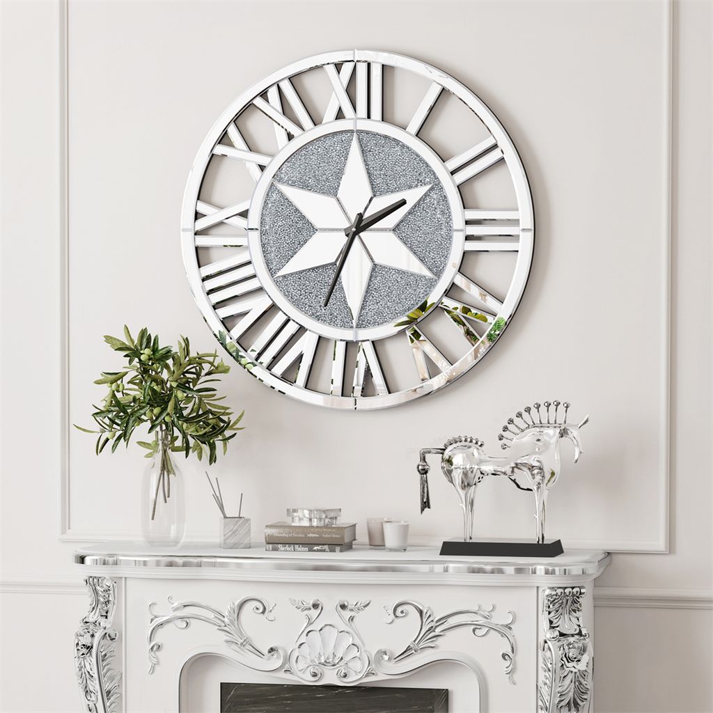 A large wall clock with Roman numerals is mounted on a wall above a decorative fireplace mantel. The mantel displays a vase of greenery and a silver horse sculpture.