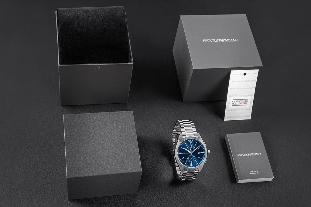 A watch and its packaging are laid out on a dark surface.