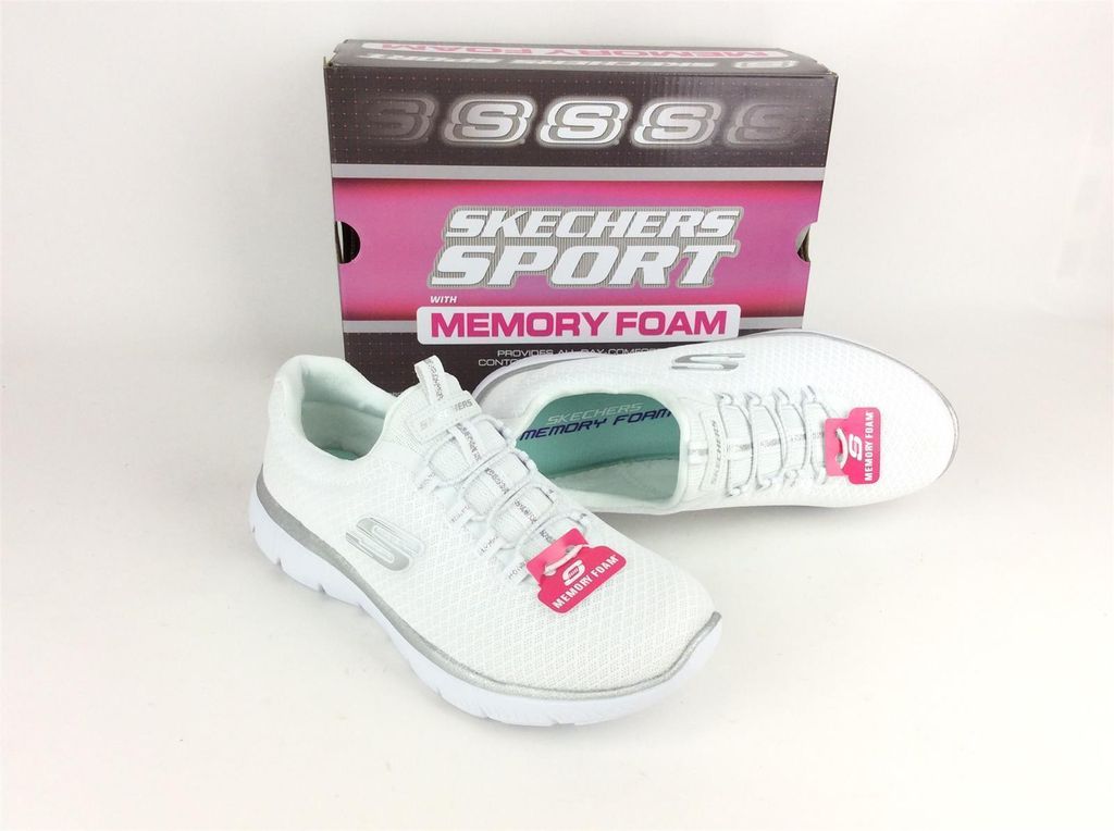 A pair of white Skechers sneakers with silver accents and a box in the background.