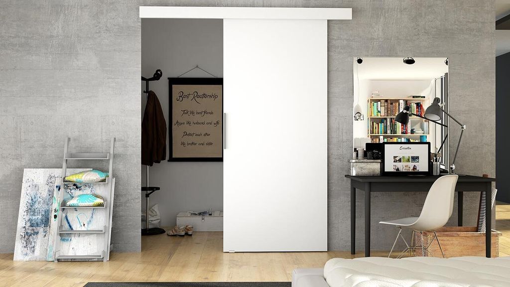 A modern interior scene featuring a white sliding door, a desk with a laptop, and decorative items.