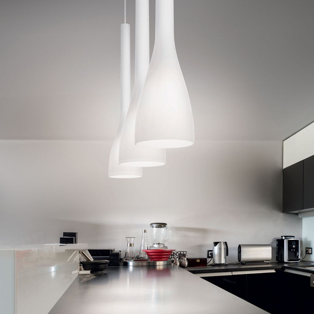 A modern kitchen counter with appliances and three pendant lights hanging above.