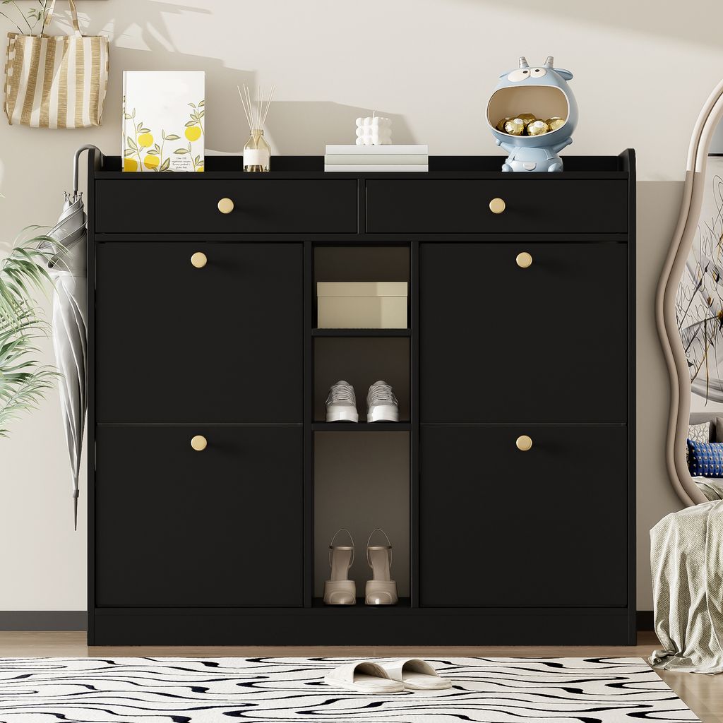 A black shoe cabinet with gold handles is shown in a room setting, with an umbrella and a plant to the left, and a mirror to the right.